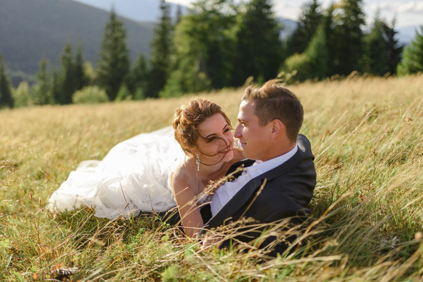 Newlyweds lying in mountain grass