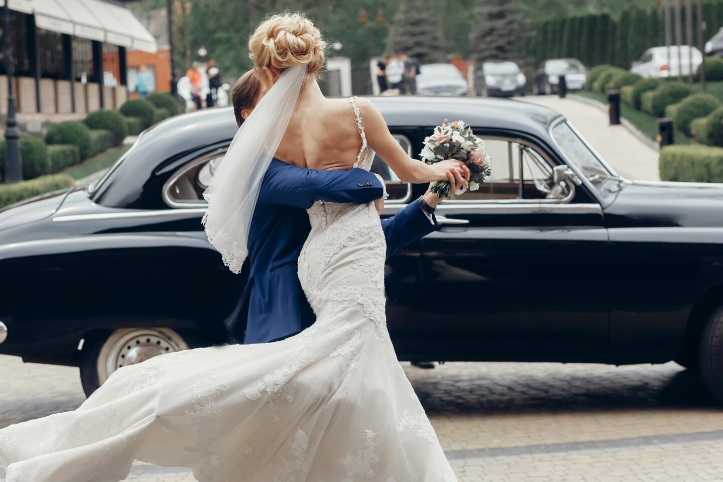 Newlyweds embracing beside a vintage car