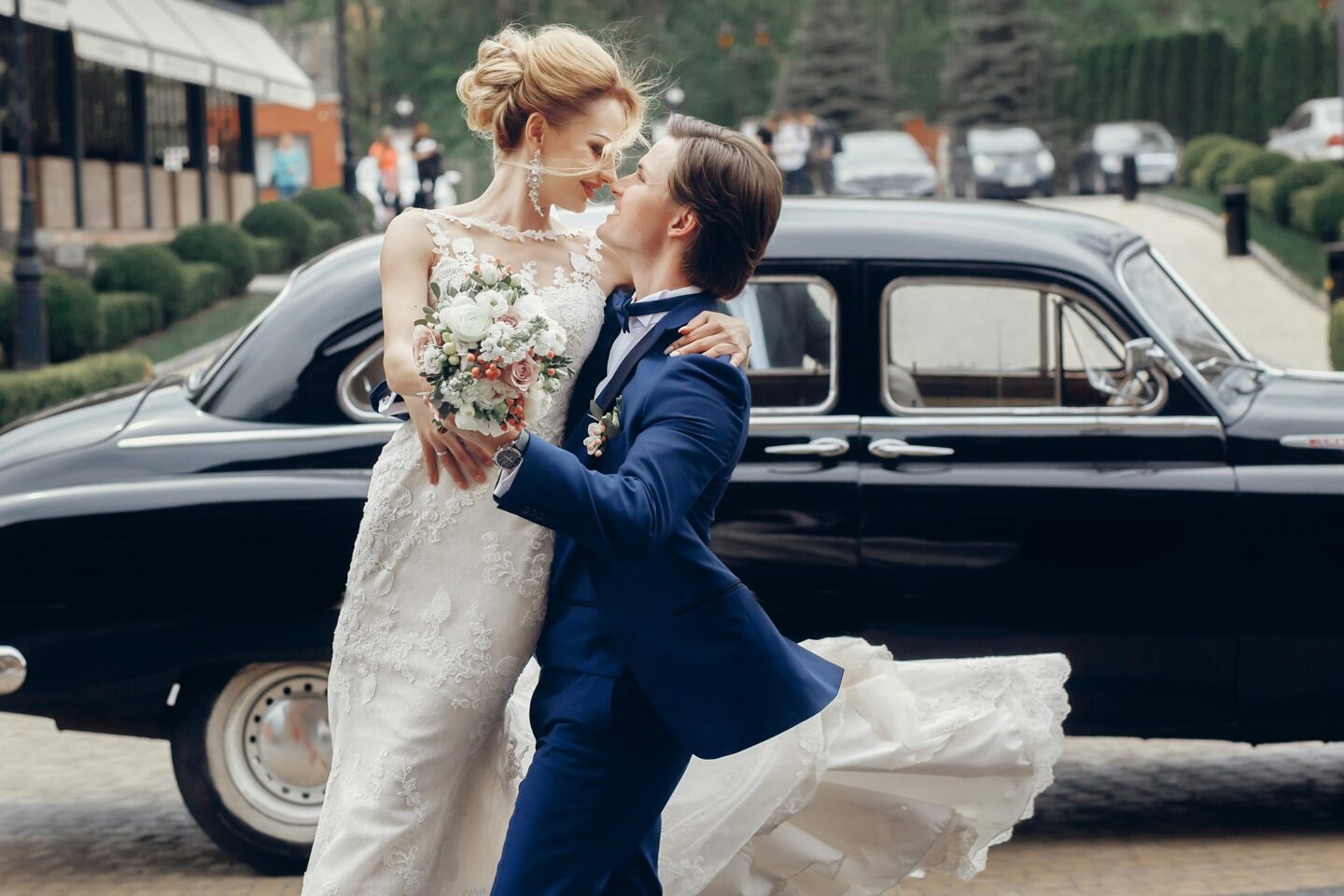 Bride and groom walking beside a vintage car